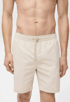 Shorts en lin beige avec une taille élastique, fermeture à cordon de serrage et poches latérales. Texture lisse et design long jusqu'aux genoux.