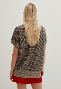 Gestrickter Kurzarmoberteil in Braun und Beige mit strukturiertem Muster, ausgestattet mit einem gerippten Saum und lockerer Passform.