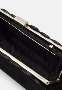 Black quilted clutch purse with gold frame and clasp, featuring "Ted Baker" branded black fabric interior lining.