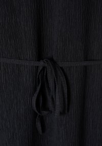 Tissu noir froissé avec une fine ceinture nouée en un simple nœud au centre.