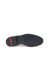 Semelle en caoutchouc noir avec un motif de bande de roulement texturé, comprenant une bande d'accent rouge. Base intérieure lisse avec une forme incurvée pour le soutien du pied.