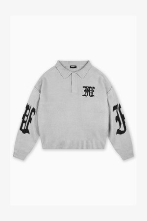 Lys grå strikket genser med krage. Har svarte broderte bokstaver på brystet og ermene, samt ribbet kant nederst og på mansjettene.