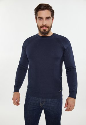 Maglione lavorato a maglia blu navy con scollatura a girocollo e polsini a costine. Presenta un motivo testurizzato, una silhouette aderente e un piccolo dettaglio del logo sull'orlo.