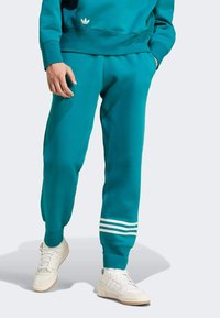 Teal sweatpants med vita tre-randiga detaljer vid fållen; tillverkade av mjukt tyg, med en avslappnad passform och elastisk midja.