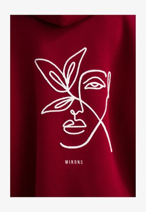 Rode hoodie met een witte geborduurde gezichtontwerp en bladaccenten, met de tekst "MIRONS" onder de afbeelding. Gladde stofstructuur.