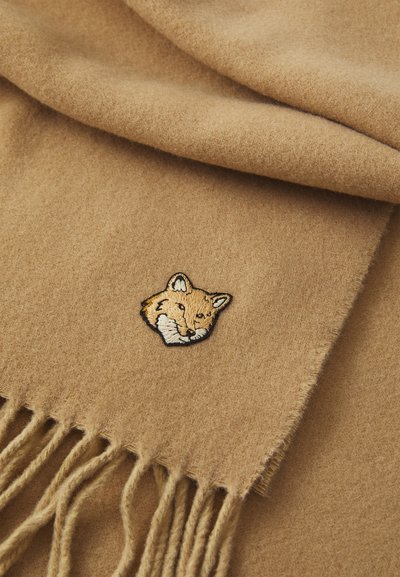 Helepruun sall, mis on valmistatud pehmest kangast, millel on tikitud rebane pea detail. Ääriste fringened annavad kujundusele tekstuuri ja aktsenti.