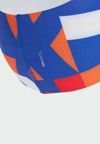 Swim shorts featuring a blue base with orange and red geometric patterns. Made from stretchy material with a visible stitching detail.