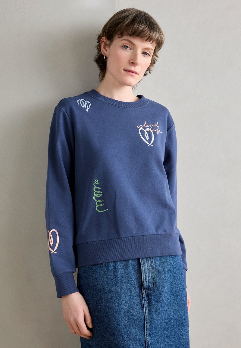 Sweatshirt marine en matière douce, avec des designs colorés brodés, un col et des poignets côtelés, et une coupe décontractée.