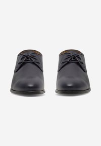 Ciemnoniebieskie skórzane buty o gładkiej fakturze, klasyczny fason na sznurówki, okrągły czubek oraz subtelne akcenty w przeszyciach. Płaska gumowa podeszwa.