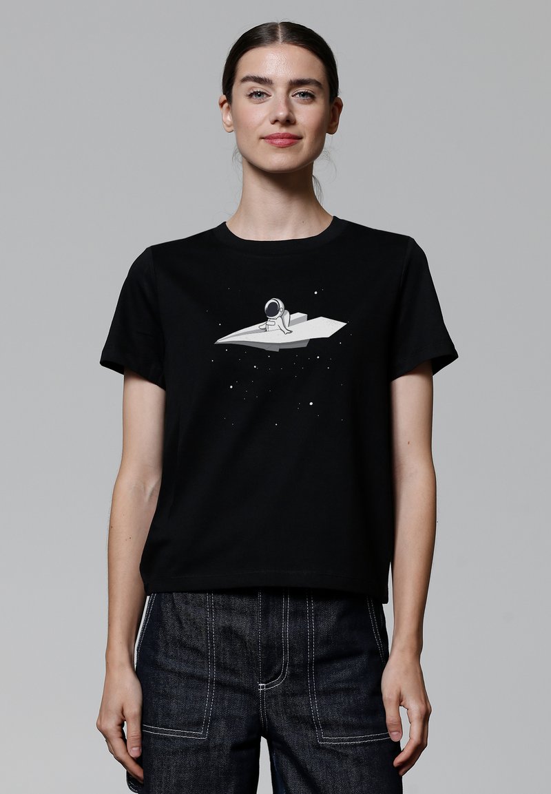 Zwarte katoenen t-shirt met een grafische afbeelding van een astronaut op een wit, hoekig object omringd door sterren. Ronde hals, korte mouwen, ontspannen pasvorm.