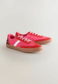 Røde og pink sneakers med overdel i ruskind, der har en hvid stribe, mønstret hæl og tekstureret gummisål. Lysende farver med snørebånd.