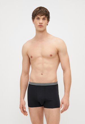 Μαύρες μποξεράκι φτιαγμένες από μαλακό ύφασμα, με ζώνη μέσης που προσφέρει άνεση και λευκές ρίγες. Στενή σχεδίαση με μέτρια ψηλή κοπή.