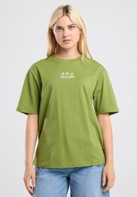 T-shirt en coton vert olive à manches courtes, col rond, avec un graphique "Goût d'été" en blanc représentant des fruits imprimé sur le devant.