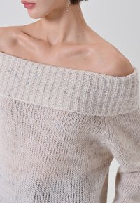 Maglione lavorato a maglia scollo a barca in beige, con scollo a coste e sottili macchie argentee su tutto il tessuto morbido e strutturato.