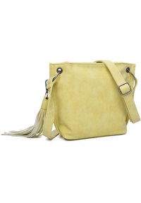 Žlutá semišová kabelka přes rameno s nastavitelným popruhem a dekorativním třásněm na boku na bílém pozadí.