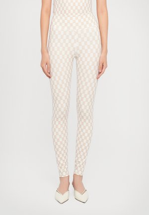 Witte leggings met een herhalend geometrisch patroon in lichtbruin. Strak aansluitende vorm met een gladde textuur, gestyled met puntige witte schoenen.