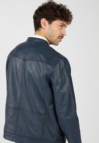 Marineblaue Lederjacke mit glatter Textur, ausgestattet mit einem klassischen Schnitt und einfachen Steppdetails. Die Rückansicht hebt die Schulternähte hervor.