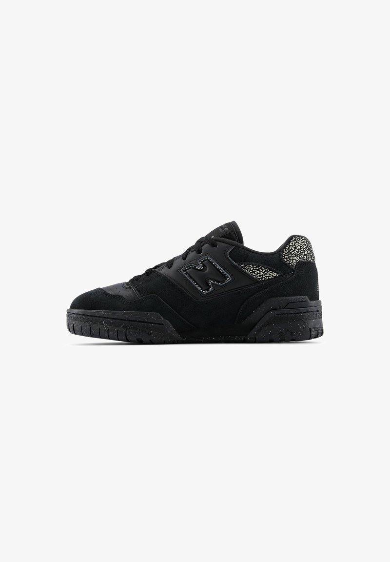Baskets noires à coupe basse avec semelle texturée, lacets à l’avant et motif à pois sur le col du talon et près du panneau du logo sur le médio-pied.