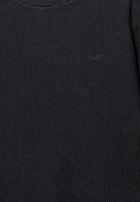 Sort tekstureret sweater med et ribbet mønster og et lille tonalt logo på fronten. Rund halsudskæring. Blødt, vævet stof.
