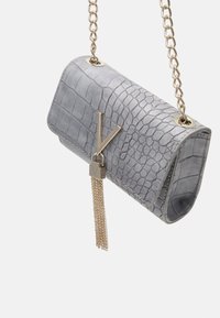 Grå handväska i krokodilmönstrad läder med en guldkedjesnodd, med en metallisk "V"-logotyp och en kedjehängseldetalj.