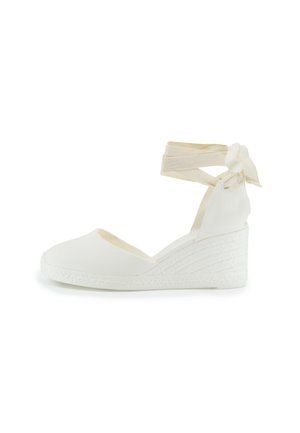 Sandalia de cuña espadrille blanca con parte superior de tela texturizada, cintas para el tobillo y suela de cuerda trenzada. Diseño sencillo y color neutro.