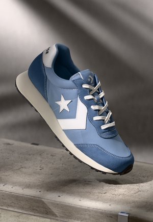 Blue sneaker featuring a suede and textile upper, white star accent, gray rubber sole, and white laces, with a rounded shape and smooth texture.