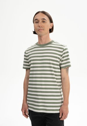 Green and white striped short-sleeve t-shirt made of cotton, featuring a crew neck and a relaxed fit, worn with black pants.