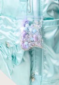 Metalna aqua torba s prozirnom vrećicom koja sadrži šarene perle i elastične trake, s srebrnim hardverom i teksturiranim materijalom.