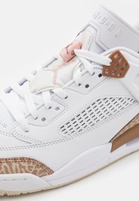 Baskets blanches en cuir et en maille. Présentent des accents roses, des détails texturés beiges, des sections perforées et une semelle en caoutchouc.