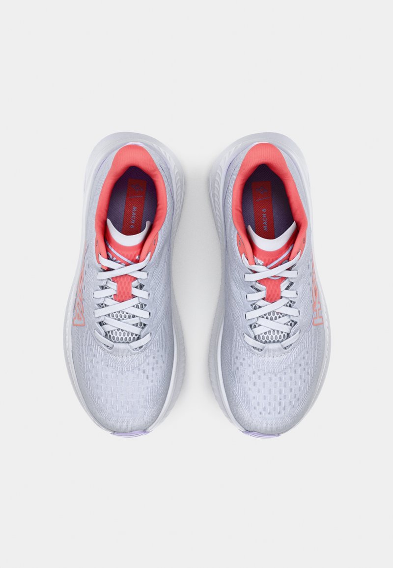 Zapatillas deportivas de color gris claro con una parte superior texturizada, cordones blancos y acentos rosas en el collar y la lengua. Presentan la marca HOKA.