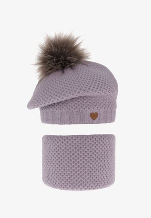 Cuffia lavorata a maglia color lilla con un pompon in ecopelliccia marrone sulla sommità e un copriorecchie coordinato. Presenta motivi testurizzati e una piccola targhetta a forma di cuore in pelle.