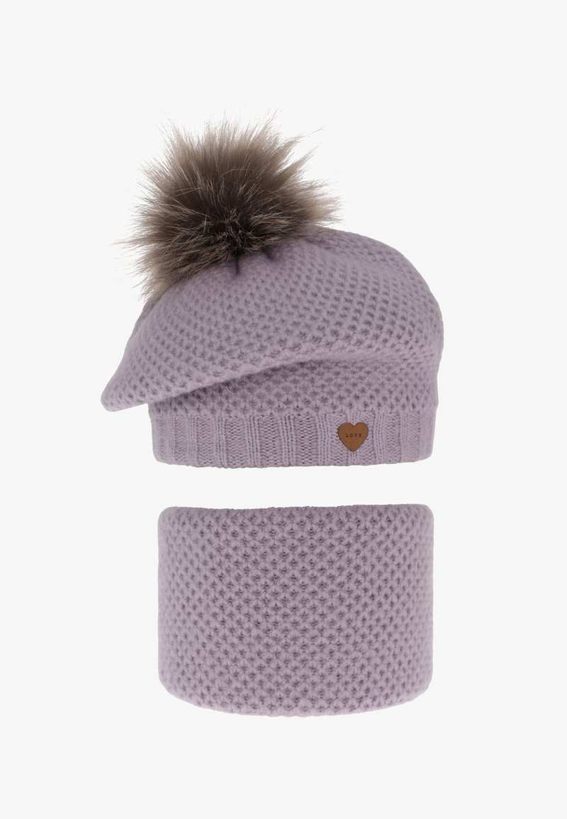 Cuffia lavorata a maglia color lilla con un pompon in ecopelliccia marrone sulla sommità e un copriorecchie coordinato. Presenta motivi testurizzati e una piccola targhetta a forma di cuore in pelle.