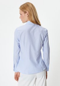 Hemd in hellblau mit gestreiftem Muster, tailliert geschnitten, lange Ärmel und klassischer Kragen. Mit knöpfbaren Manschetten und einer glatten Stofftextur.