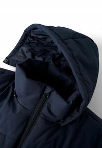 Doudoune navy avec capuche, présentant un col montant, une fermeture éclair à l'avant et une texture lisse. Le tissu a un motif en grille subtil.