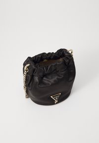 Schwarze Satin-Einkaufstasche mit gerafftem oberen Teil, goldener Kettenriemen und einem dreieckigen Logo-Anhänger auf der Vorderseite. Glatte Textur, minimalistische Gestaltung.