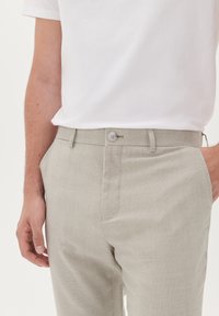 Light gray plaid trousers with a button closure, featuring a smooth texture and a tailored fit. Paired with a plain white t-shirt.