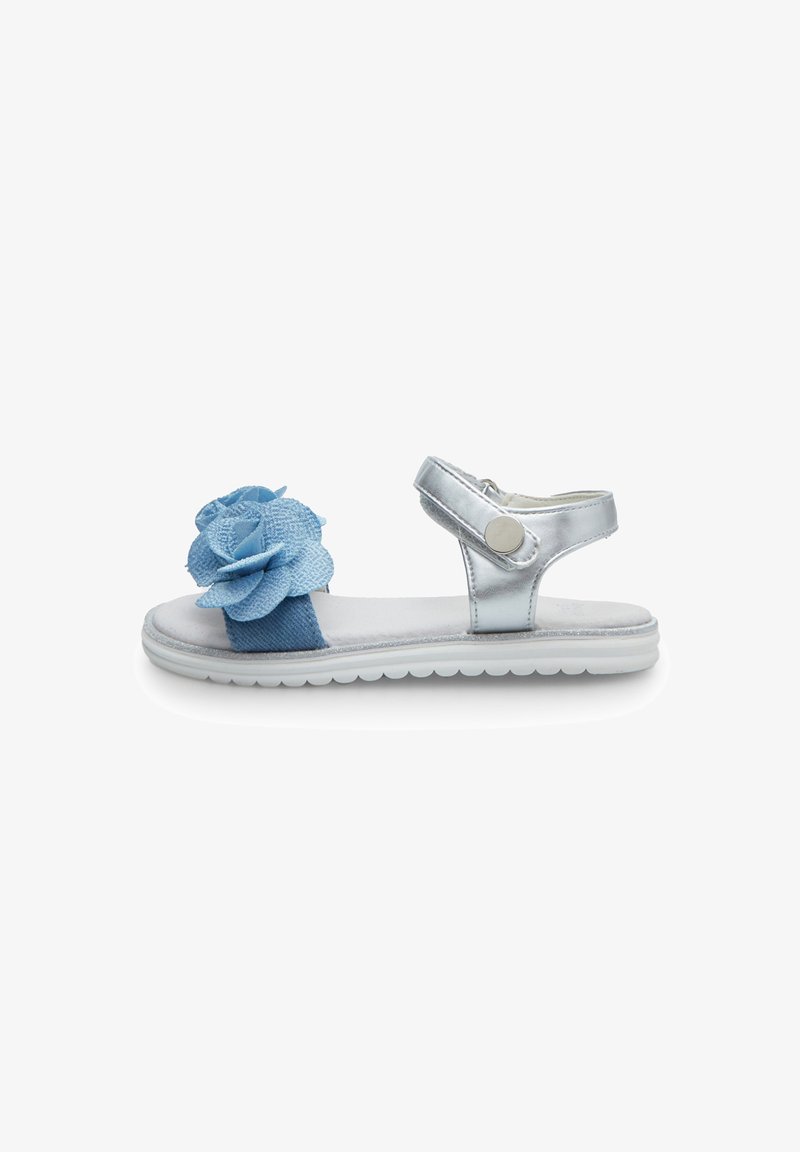 Silver metallic sandal with blue fabric flower accent, ankle strap closure, and white textured sole. Flat design, suitable for casual wear.