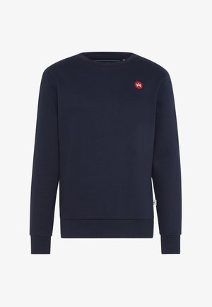 Sötétkék pulóver puha pamutból, kerek nyakkal, hosszú ujjakkal, és egy kis kontrasztos piros logóval a mellkason.