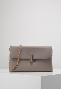 Šedá kožená kabelka s překlopným designem, zlatým řetízkovým popruhem a obdélníkovým kovovým akcentem na přední straně. Texturovaný povrch.