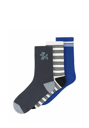 Trois chaussettes mi-mollet dans un ensemble : gris avec une petite icône de chien, blanc à rayures noires, et bleu uni avec des rayures blanches en haut.