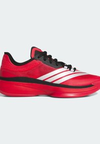 Chaussure de sport rouge avec lacets noirs, motif à trois bandes blanches sur les côtés et semelle épaisse et amortissante sur fond clair.