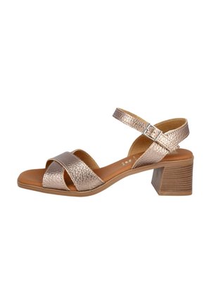 Sandalia de tacón metálica color rosa dorado con tiras cruzadas, correa de tobillo ajustable, parte superior texturizada y diseño de tacón cuadrado.
