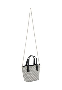 Struktureret, mønstret totebag i hvid og sort med en diamantdesign. Den har sorte håndtag og en sølv kædetras.