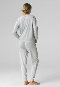 Szary zestaw bluzy i dresów wykonany z miękkiej, lekkiej tkaniny. Charakteryzuje się ściągaczami na mankietach oraz luźnym krojem, a także minimalnym detalowaniem szwów.