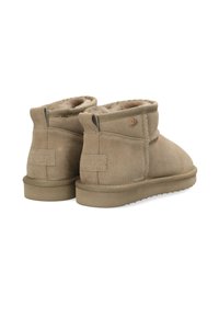 Bruna mocka ankellängda stövlar med en fluffig foder, platt gummisula och sömnadsdetaljer. Har en liten metallisk logotyp på sidan.