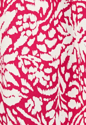 Gros plan sur un tissu rouge avec un motif floral abstrait blanc irrégulier et un tissage texturé.