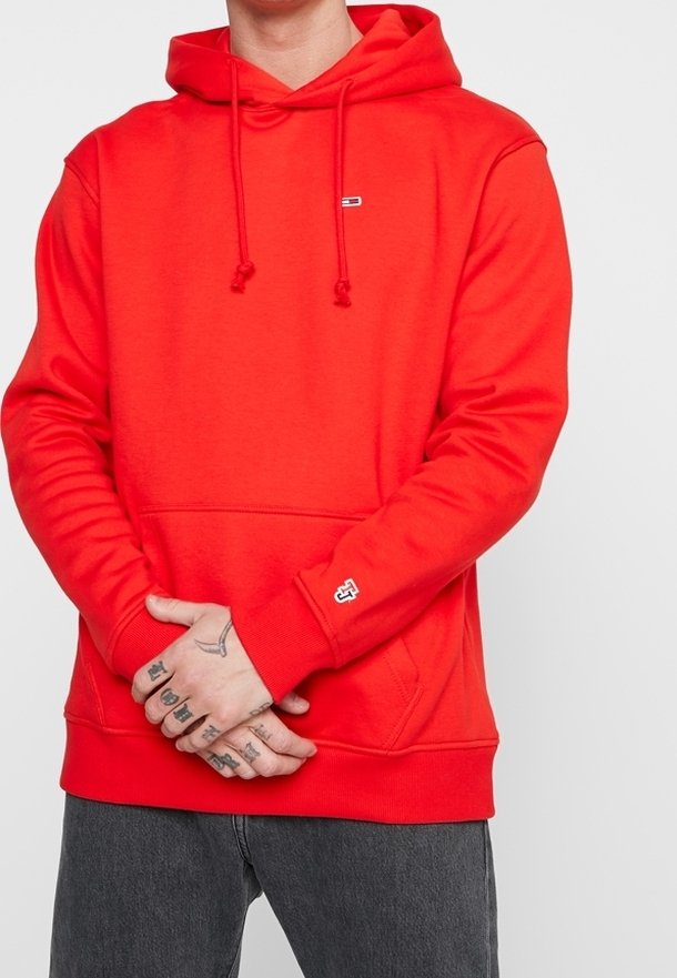 Felpa con cappuccio rosso realizzata in tessuto morbido, presenta cordini regolabili, una tasca a marsupio frontale e un logo sul petto.
