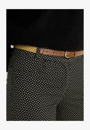 Pantalon noir à motifs avec des dessins triangulaires crème, assorti d'une ceinture en cuir marron avec une boucle dorée et une texture tissée.