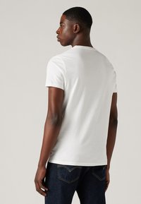 Tricou din bumbac alb, cu mânecă scurtă și decolteu rotund. Țesătura pare netedă, fără modele sau accente vizibile.