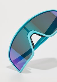 Et par turkise sports solbriller med wraparound-design, med gradient lilla linser og gummi detaljer for komfort.